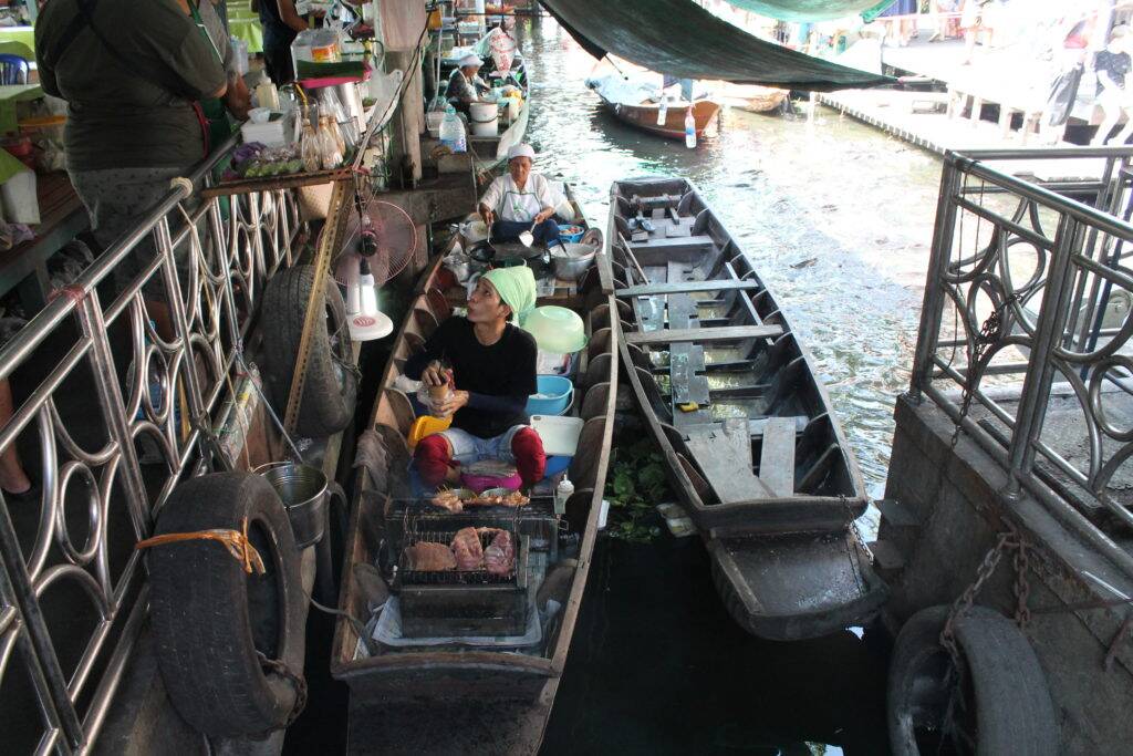 Tailandês assando peixe em um dos barcos do canal do Taling Chan Tailandês assando peixe em um dos barcos do canal do Taling Chan