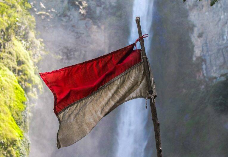 Bandeira da Indonésia em frente a cachoeira de Si Piso Piso no Lake Toba, em Sumatra, Indonésia